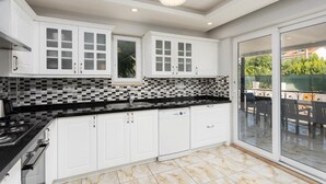 Una cocina moderna con armarios blancos, encimera negra y salpicadero de azulejos.