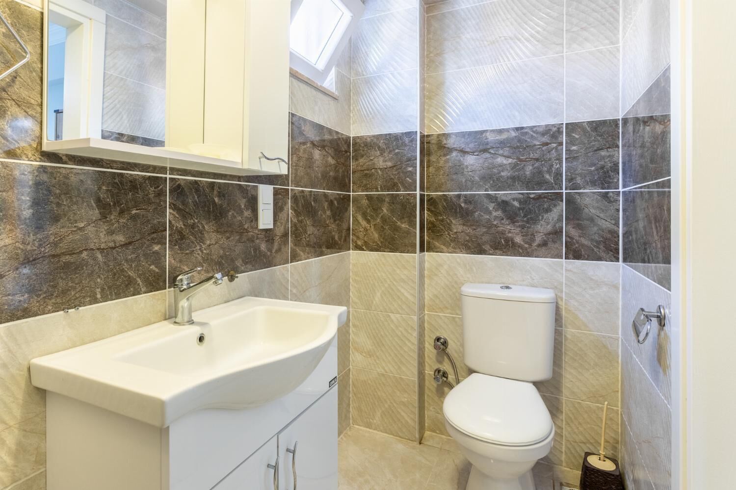 Een badkamer met een witte wastafel, toilet en muren met een marmerlook.