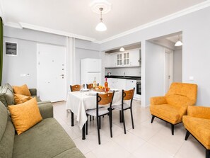 Ein modernes Wohnzimmer mit einem Esstisch, Stühlen, einer Couch und einem orangefarbenen Sessel.