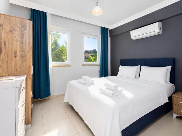 A hotel room with a bed, a wardrobe, a window with curtains, an air conditioning unit, and a view of greenery outside. - Villa Kaya 1 - Five Bedroom Villa, Sleeps 12 (Dalyan)