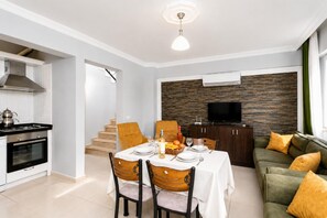 A modern living space with a kitchen, dining area, and a living room with a TV and sofa.