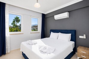 A hotel room with a bed, two windows, an air conditioning unit, a bedside table, and a nightstand. - Villa Kaya 1 - Five Bedroom Villa, Sleeps 12 (Dalyan)
