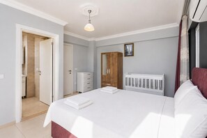 A bedroom with a bed, a wardrobe, a radiator, and a door leading to a bathroom.
