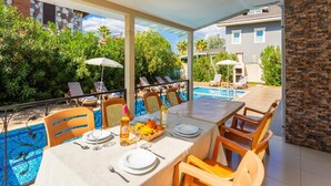 A covered outdoor dining area with a pool, lounge chairs, and a table set for two. - Villa Kaya 2 - Five Bedroom Villa, Sleeps 12 (Dalyan)
