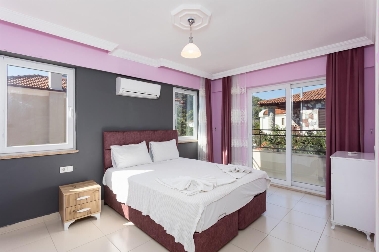 Un dormitorio con cama, mesita de noche, armario y balcón con vistas.