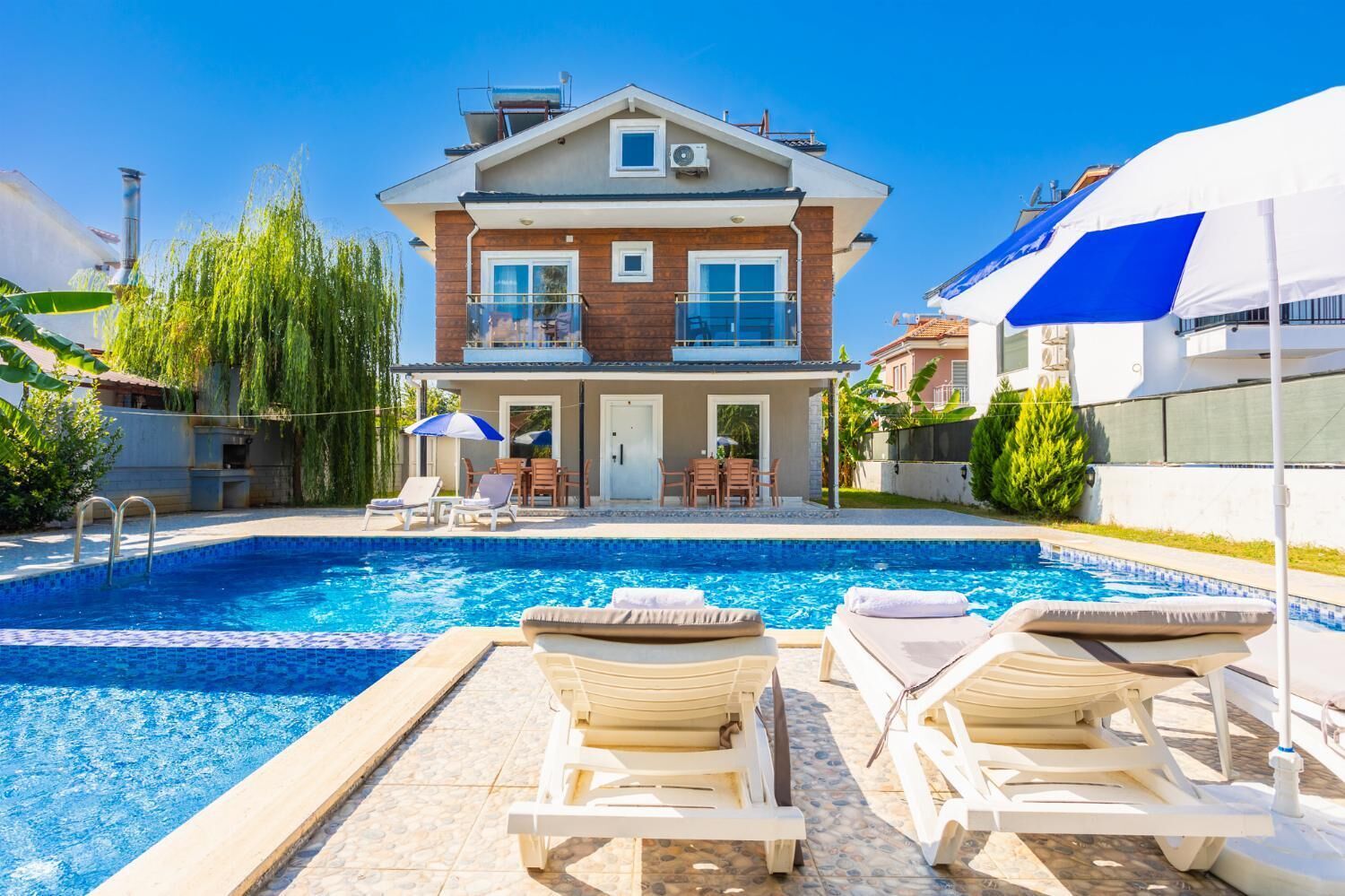 Una casa moderna de dues plantes amb piscina, mobles d'exterior i una zona de terrassa.