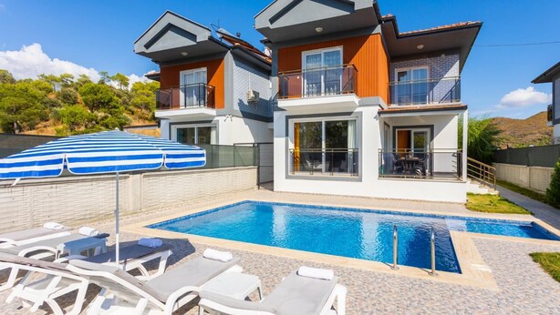 A modern two-story house with a swimming pool, lounge chairs, and a blue-striped umbrella. - Villa Sasha 2 - Four Bedroom Villa, Sleeps 10 (Ortaca)