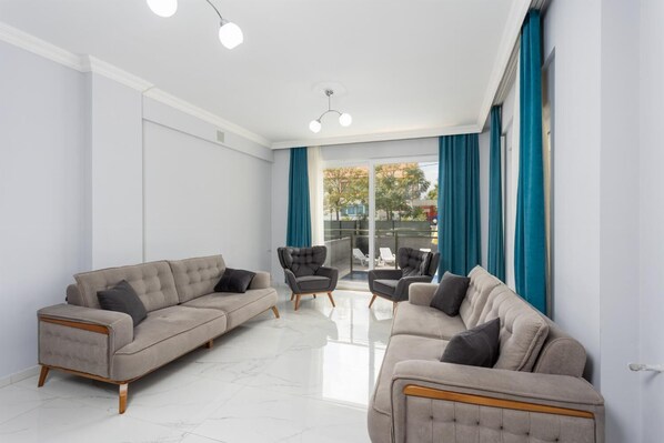 A modern living room with two sofas, a coffee table, and a chair. The room has large windows with blue curtains and a view of the outside. - Villa Sasha 2 - Four Bedroom Villa, Sleeps 10 (Ortaca)