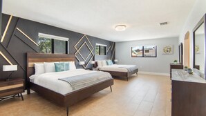 A modern bedroom with two beds, a wooden headboard, and a nightstand with a lamp. - Retreat Near Hard Rock • Pool, BBQ & Game Room (Miami Gardens)