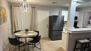 A modern kitchen with a built-in refrigerator, a dining area with a round table and chairs, and a pendant light above the table. - Round Rock Supernova minutes from Kalahari, Round Rock Sports Complex, and DT  (Round Rock)