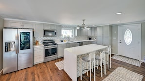 A modern kitchen with stainless steel appliances, a central island, and patterned chairs. - Weymouth Waterfront Getaway w/ Swim Spa & Hot Tub (Weymouth)