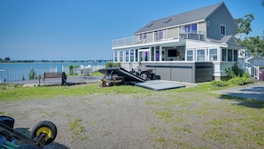 A two-story house with a balcony, a garage, and a dock extending into a lake. - Weymouth Waterfront Getaway w/ Swim Spa & Hot Tub (Weymouth)