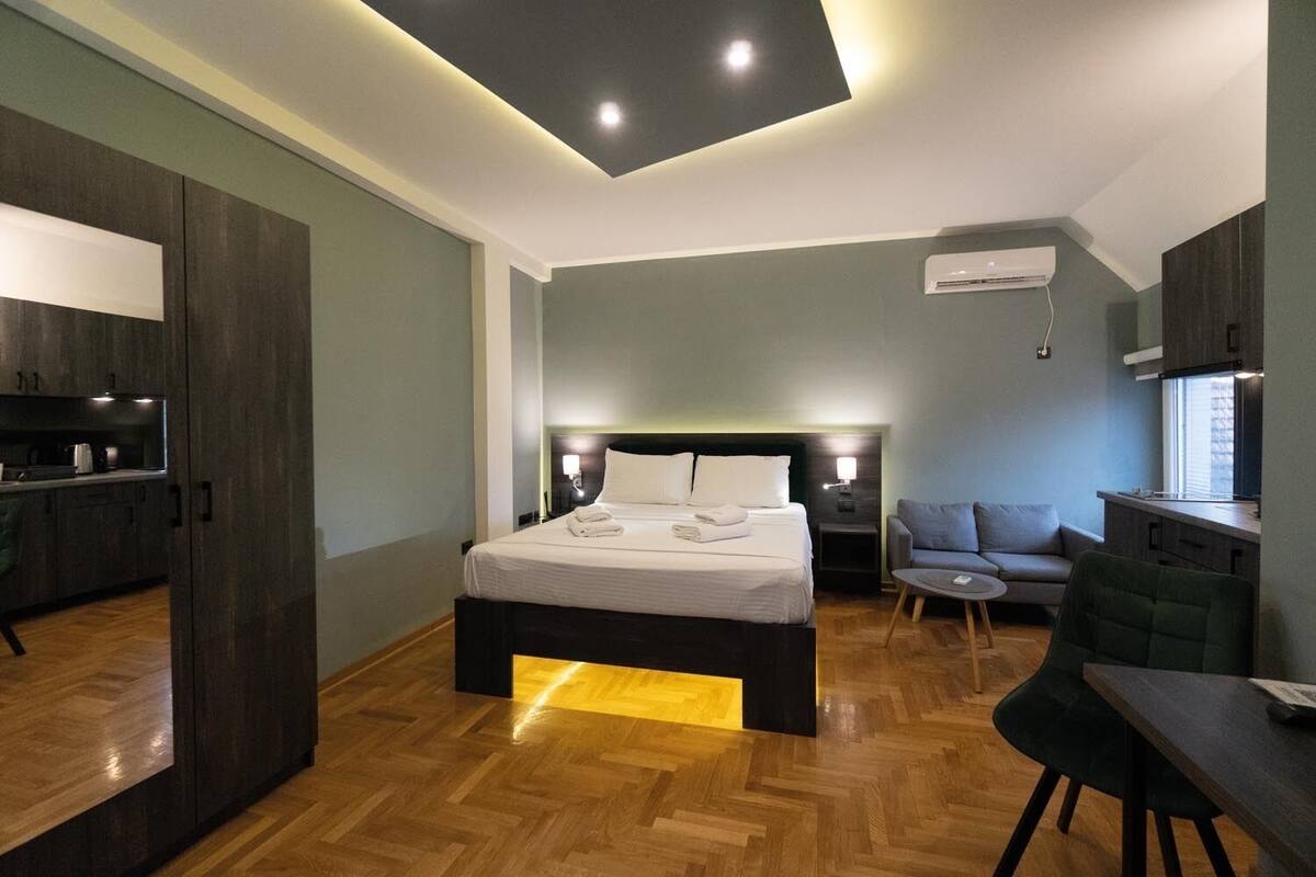 Ein modernes Hotelzimmer mit einem großen Bett, einem Schreibtisch, einer Couch und einer Küchenzeile.