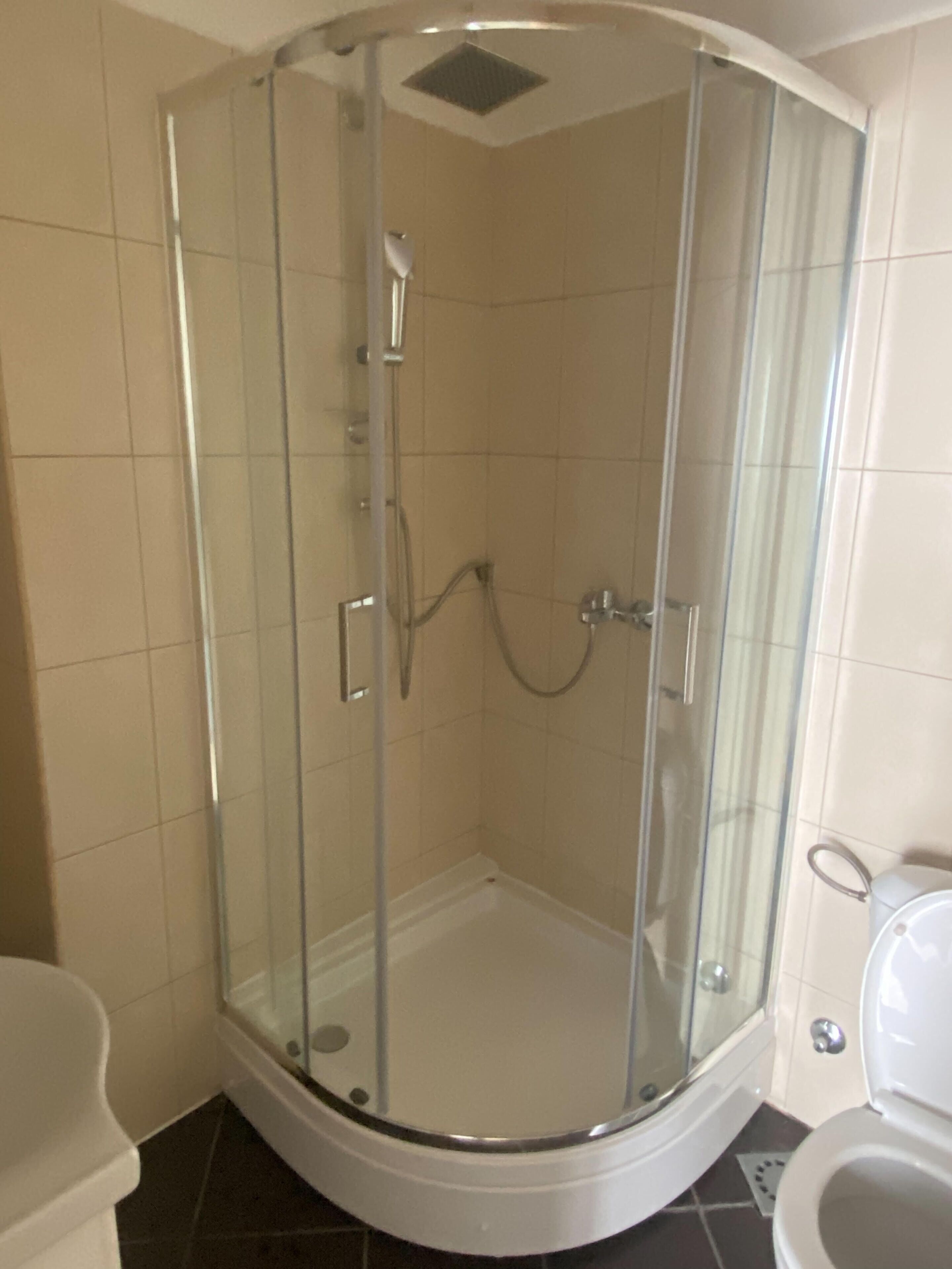 Eine Duschkabine aus Glas mit Toilette und Waschbecken in einer Eckbadewanne.