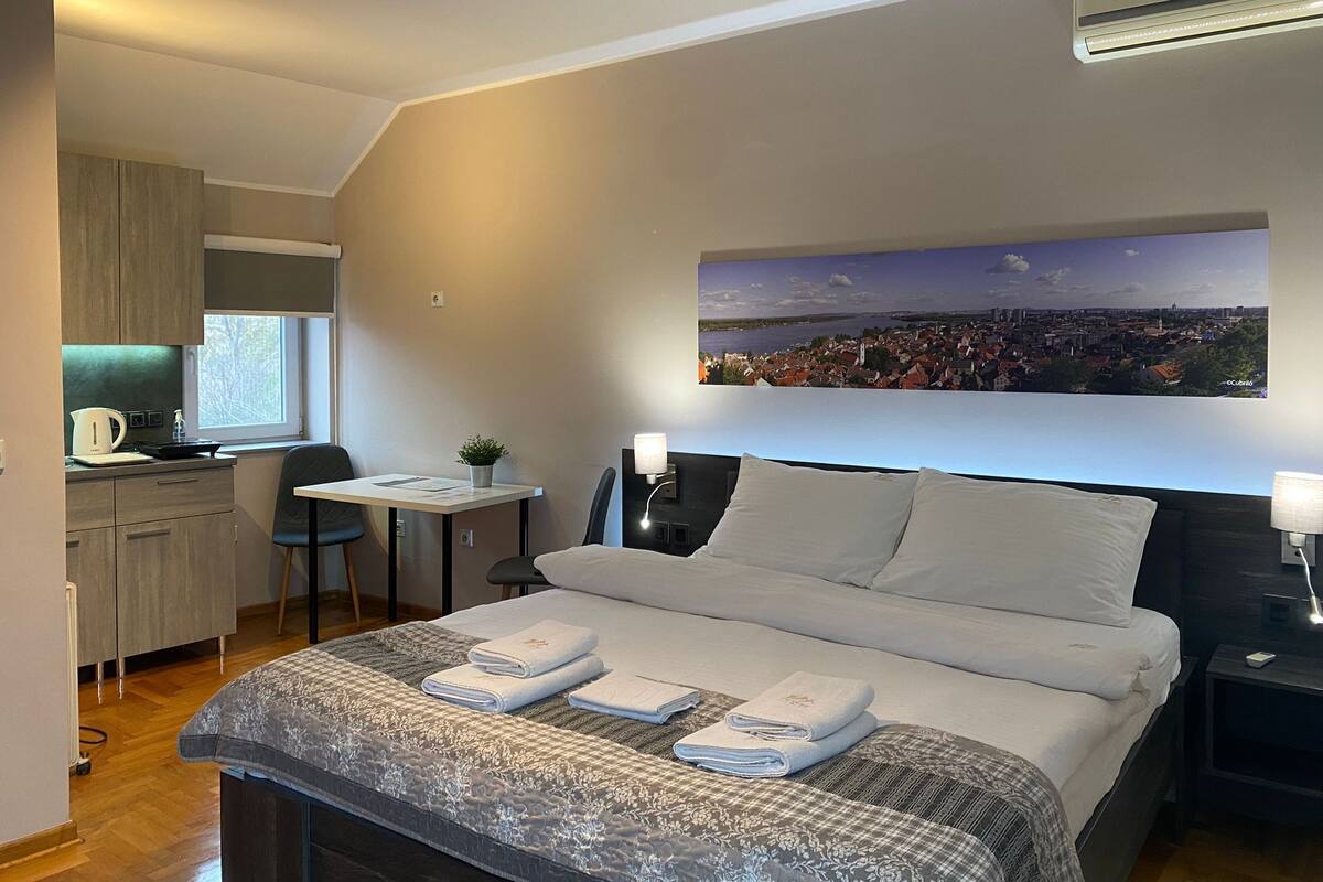 Ein modernes Hotelzimmer mit einem Bett, einem Schreibtisch und Blick auf die Stadtlandschaft.