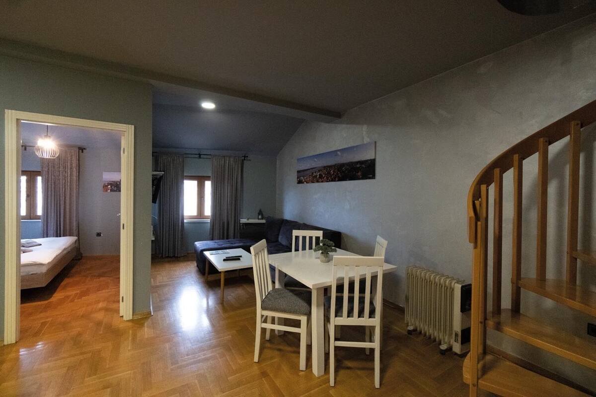 Ein kompakter Wohnbereich mit Essbereich, Sofa, Bett und Treppe.