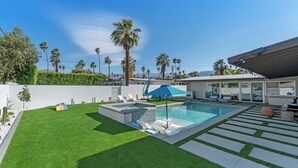 A modern outdoor pool area with a rectangular pool, lounge chairs, and a blue umbrella. - Poolside at Panorama - Walk to El Paseo (Palm Desert)