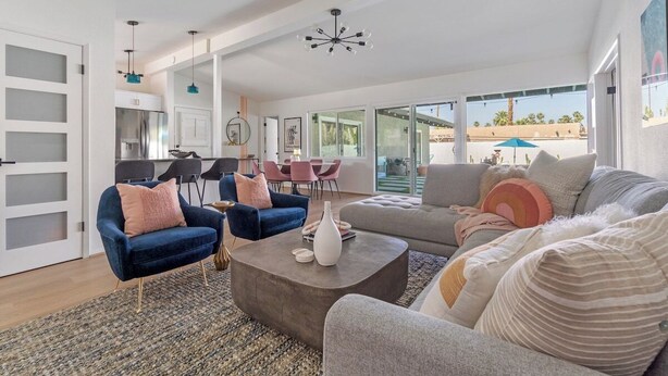 A spacious living area with a sofa, two armchairs, a coffee table, and a dining area with chairs and a table. - Poolside at Panorama - Walk to El Paseo (Palm Desert)