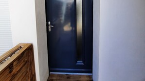Eine dunkelblaue Tür mit silberner Klinke, eine Holzbank links und ein kleiner Teppich im Eingangsbereich.