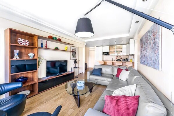 A modern living room with a sofa, coffee table, and TV. There is a kitchen in the background. - Muette - Spontini 1bdr by B'Your Home (Paris)