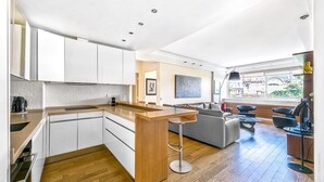Una cocina moderna con una isla central, armarios blancos y suelo de madera.