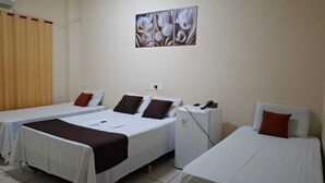 Habitación de hotel con dos camas individuales, un escritorio pequeño con teléfono y aire acondicionado de pared.