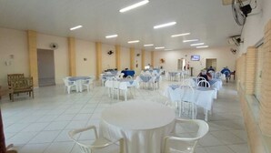 Un espacio interior amplio con varias mesas y sillas redondas, paredes blancas y ventiladores de techo.