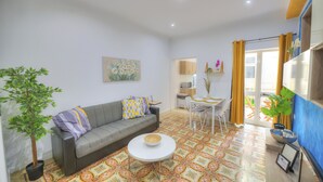 A living room with a grey sofa, a round coffee table, a potted plant, and a colorful patterned floor. - Charming 2 bedroom townhouse, internal yard JDES1-1 (Gzira)