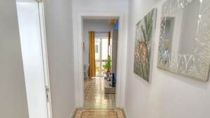 A hallway with patterned floor tiles, a door on the left, and a mirror on the right. - Charming 2 bedroom townhouse, internal yard JDES1-1 (Gzira)