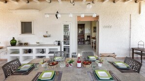 A dining area with a rustic ceiling, white walls, and a wooden table set for four.