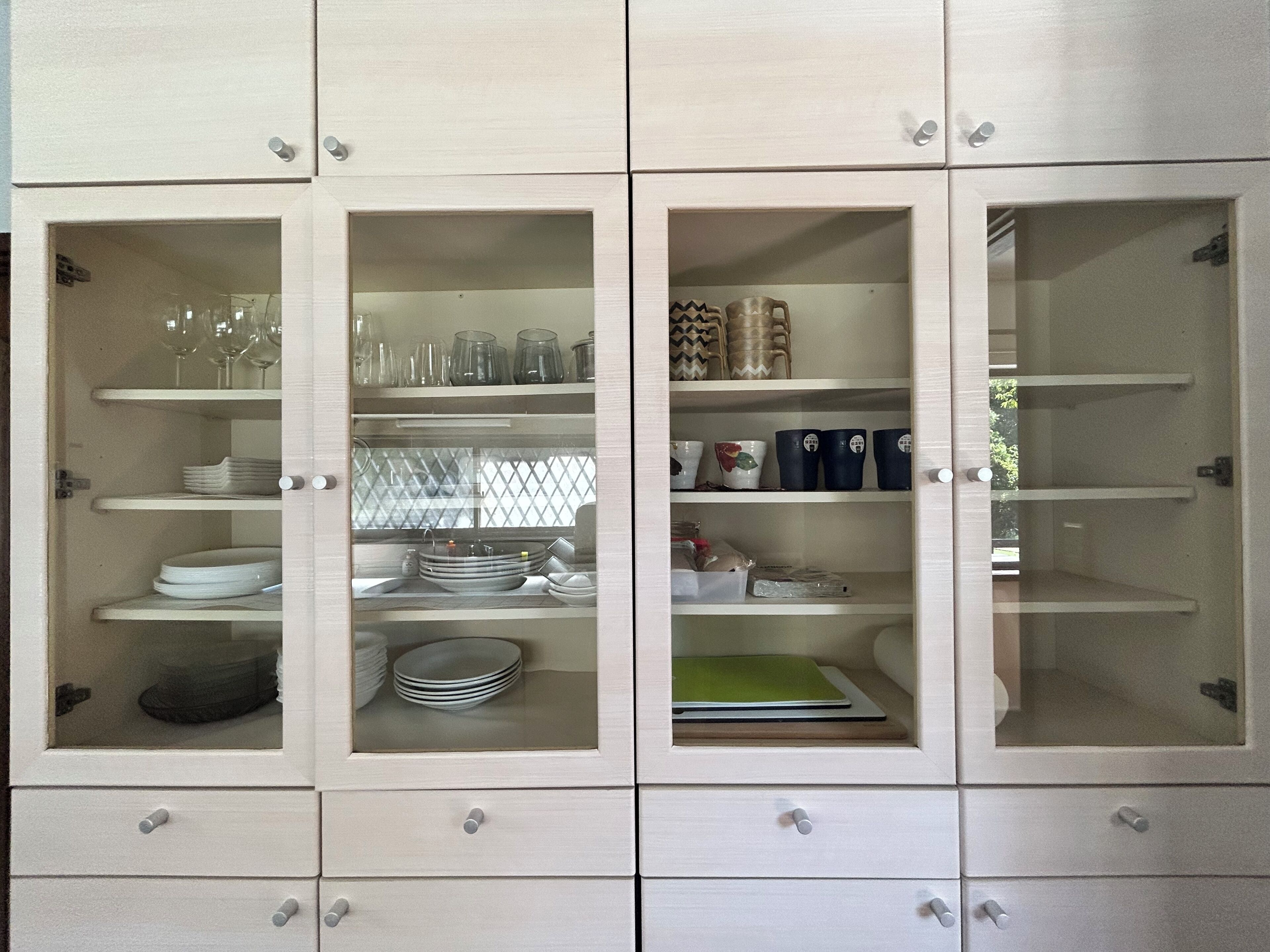 Ein Schrank mit mehreren Regalen und Schubladen, der verschiedene Küchenutensilien und Geschirr beherbergt.