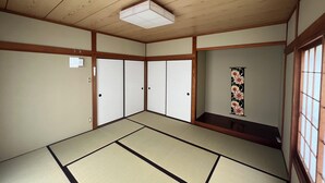 Una habitación japonesa tradicional con suelo de tatami, puertas correderas y una lámpara en el techo.