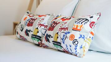 A neatly made bed with white linens and colorful pillows.