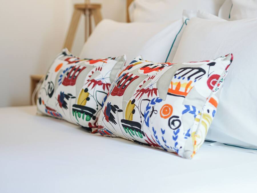 A neatly made bed with white linens and colorful pillows.