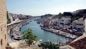 A marina with boats docked along the waterfront, surrounded by buildings and a clear sky.