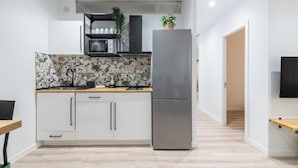 A modern kitchen with white cabinets, a stainless steel refrigerator, and a microwave.