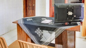 Ein hölzerner Empfangstresen mit gemustertem Tischläufer, einem Fernseher und einem Schild über der Tür.