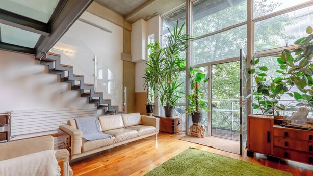 A modern living room with a staircase, a sofa, a green rug, and large windows. - Incredible 2BD Loft by Regents Canal - Haggerston (London)