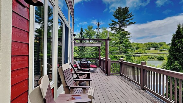 A wooden deck with outdoor seating, a pergola, and a scenic view of a lake and forest. - At the Start of It All by Taylor Made Deep Creek (McHenry)