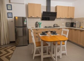 Eine moderne Küche mit Holzschränken, einem Edelstahlkühlschrank, einem Gasherd und einem Esstisch mit Stühlen.