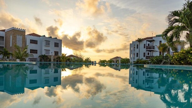 Uma piscina de hotel tranquila com reflexo límpido dos edifícios e do céu.