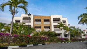 Um hotel com vários andares, fachada branca, varandas e entrada central.