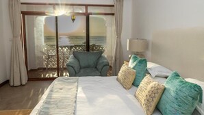 A bedroom with a bed, a chair, a lamp, and a view of the sea through a large window. - The Sultan Palace Beach Retreat Three-Bedroom Villa (Kikambala, Mombasa)