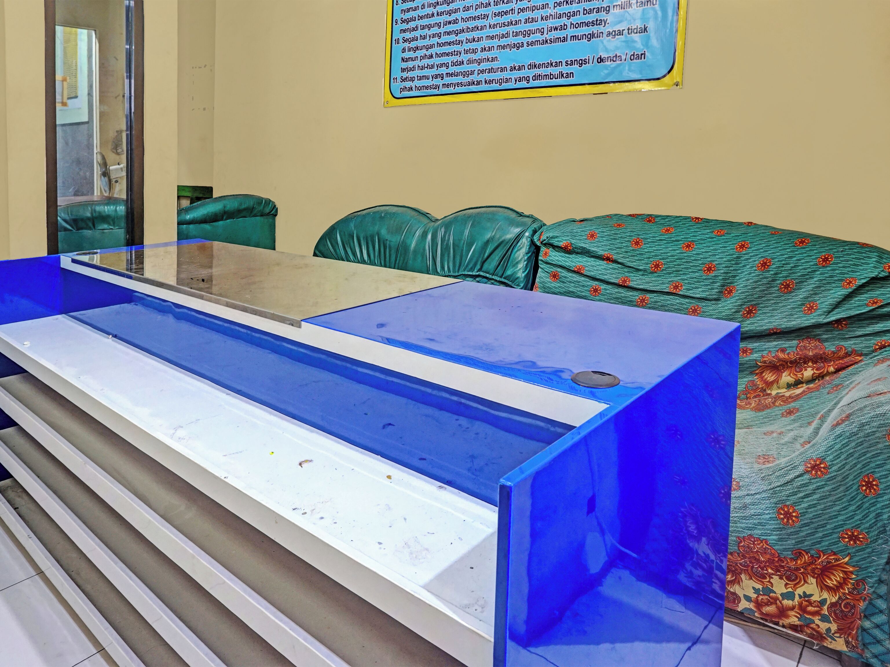A reception area with a blue counter, green cushioned seating, and a wall-mounted sign with text.