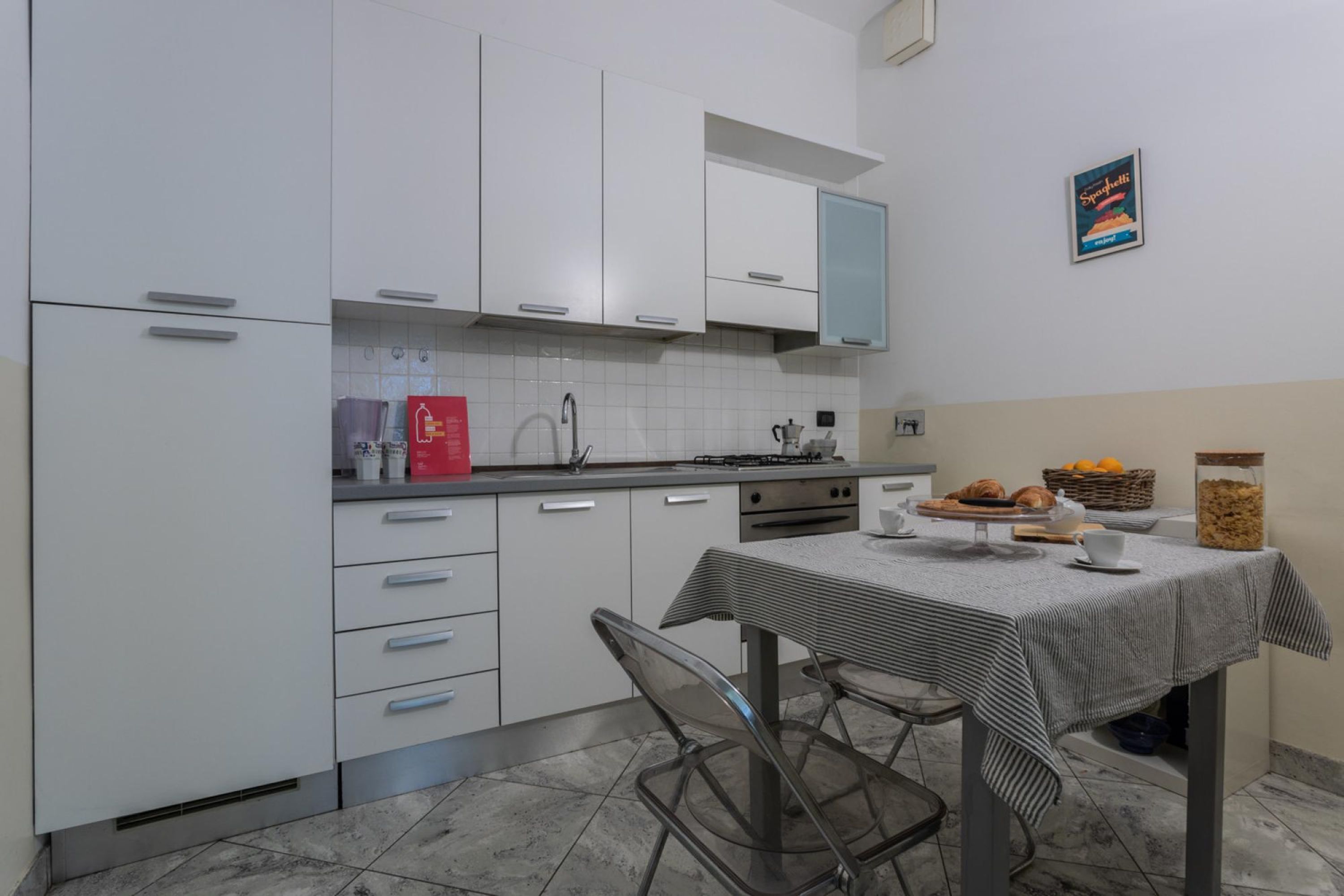Una cocina moderna con armarios blancos, una estufa a gas y una mesa de comedor cubierta con un mantel a rayas.