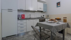 A modern kitchen with white cabinets, a gas stove, and a dining table set with a striped tablecloth.