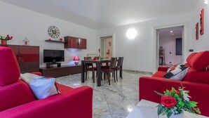 A modern living room with red sofas, a dining table, and a TV.