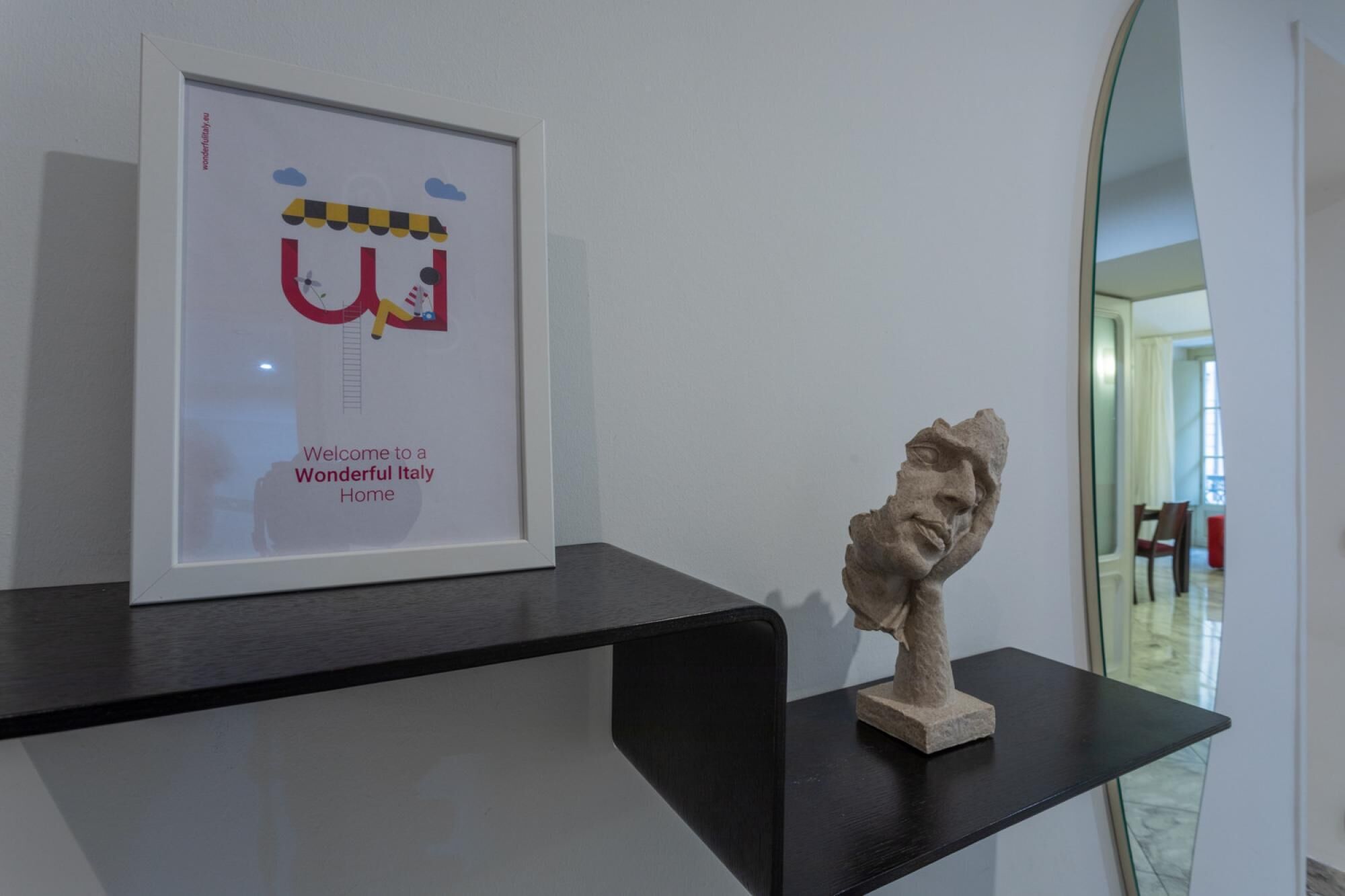 A framed picture with a cartoon character and text, and a sculpture on a black shelf.