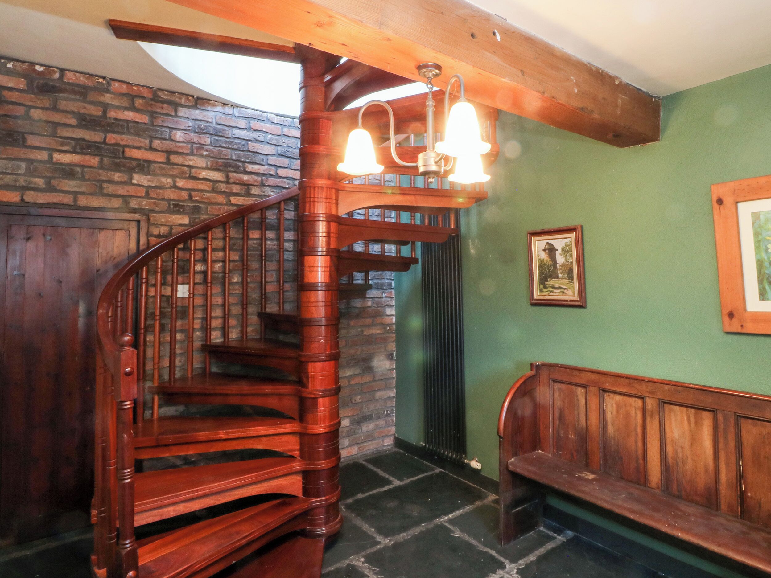 Una escalera en espiral de madera con un banco en la parte inferior.