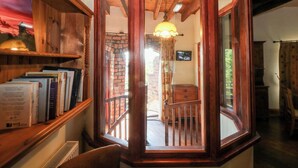 Ein Eckzimmer mit einem achteckigen Holzfenster, einem Bücherregal und einem Deckenventilator.